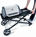 Broil King Porta-Chef AT220 portable gas grill being lowered into folded position by a person, highlighting the collapsible cart system, side shelf, and compact storage design.