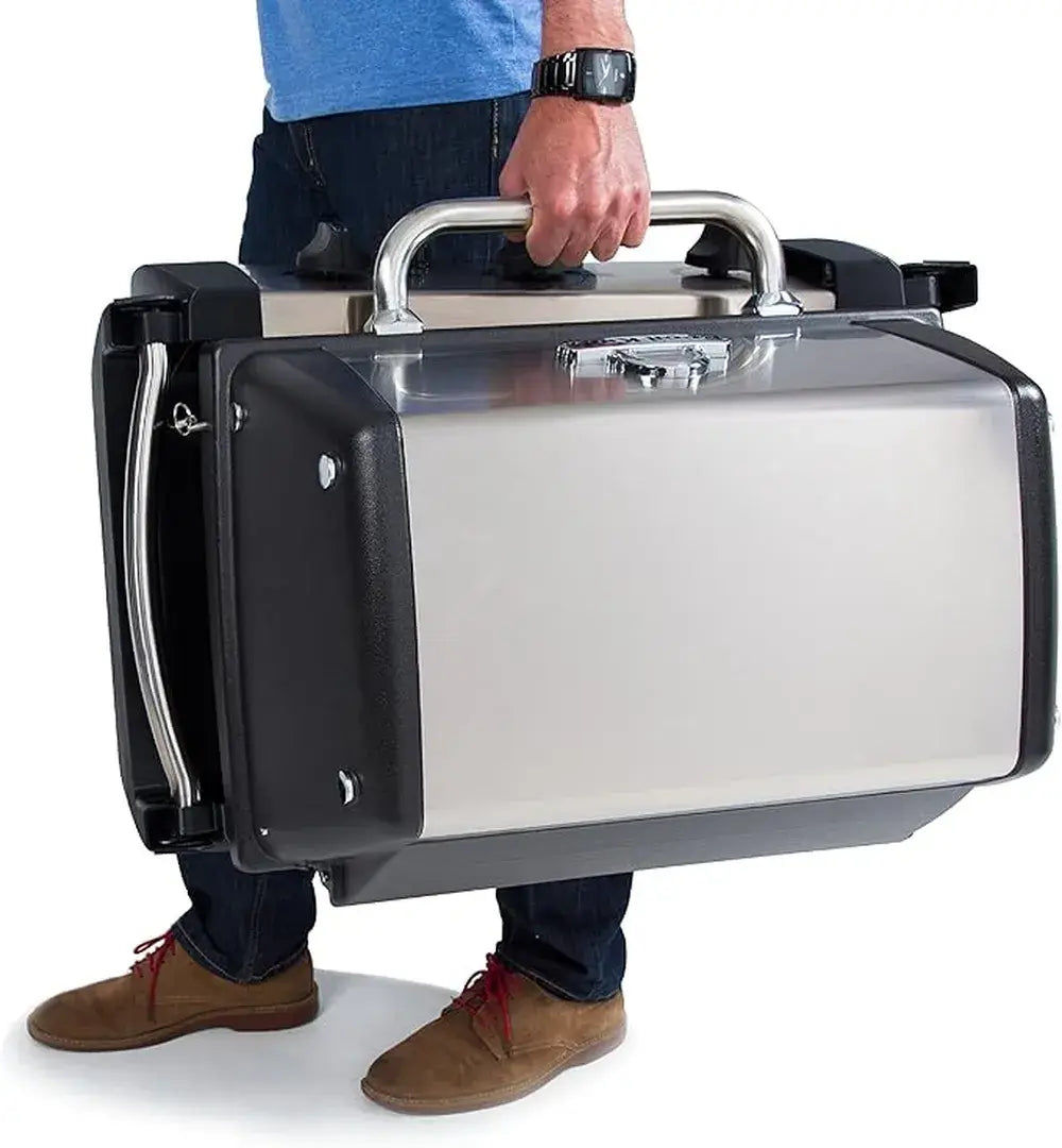 Person carrying the folded Broil King Porta-Chef 320 portable gas grill by its large stainless steel handle, highlighting the compact travel-friendly design.