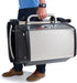 Person carrying the folded Broil King Porta-Chef 320 portable gas grill by its large stainless steel handle, highlighting the compact travel-friendly design.