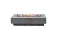 Lit Elementi Hampton OFG139LG Fire Table 56" in light gray GFRC with linear flames and lava rocks.