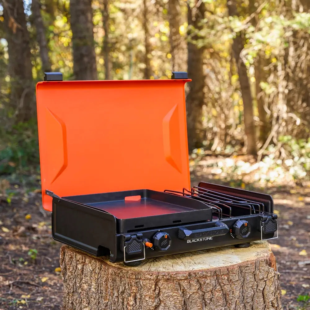 Rear angle of black camping griddle showing propane hookup and side burner tray