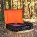 Rear angle of black camping griddle showing propane hookup and side burner tray