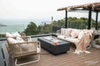 Elementi Granville OFG121DG Fire Table 60" Dark Gray covered with a stainless steel lid on a rooftop terrace.