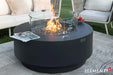 Elementi Plus Nimes fire table with glass wind guard and burning fire glass.