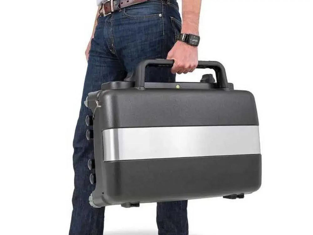 Person carrying the compact Broil King Porta-Chef Stove 200 by its top handle, highlighting the portable suitcase-style design.