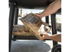 Hands placing a bag of hardwood lump charcoal on the lower storage shelf of the Broil King Regal Charcoal Offset 400 smoker grill.