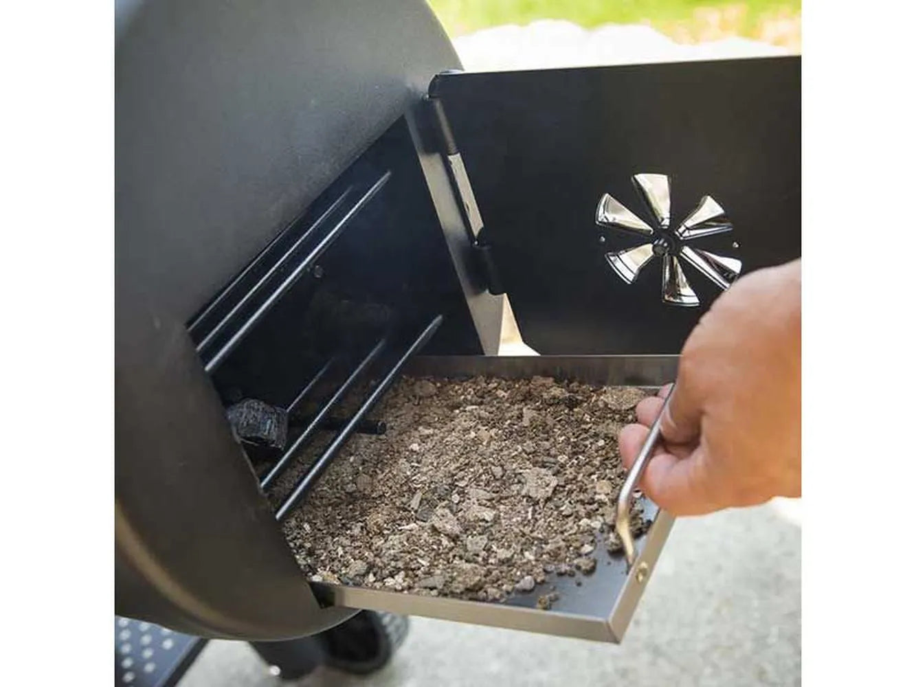 Pull-out ash tray being removed from the Broil King Regal Charcoal Offset 400 smoker grill for quick ash cleanup.