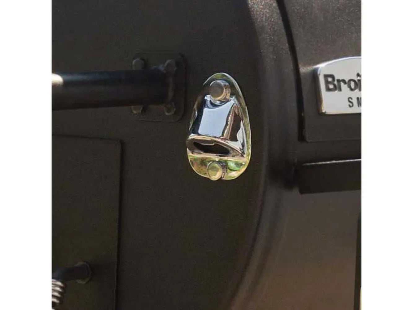 Close-up of the built-in bottle opener mounted on the side of the Broil King Regal Charcoal Offset 400 smoker grill.