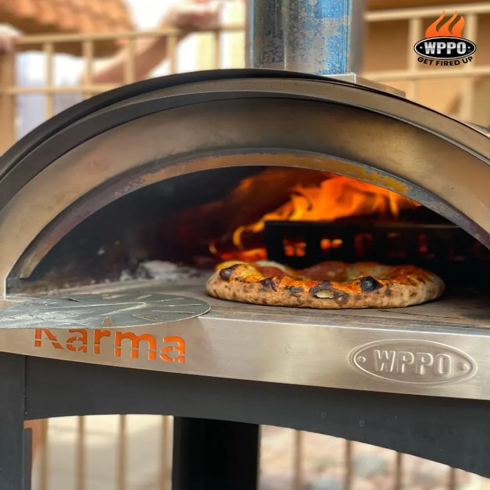 Pizza baking inside WPPO Karma 25 wood-fired oven with open flame, arched mouth, Karma logo, and WPPO badge.