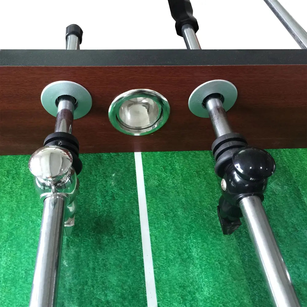 A close-up, downward-facing view of the center field on the Hathaway Metropolitan 54-inch Foosball Table, showing the rods, players, and the ball entry port.