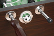 Foosball table close-up showing a black-and-white soccer ball in a chrome ball return slot, flanked by metal rods with ergonomic wooden handles.