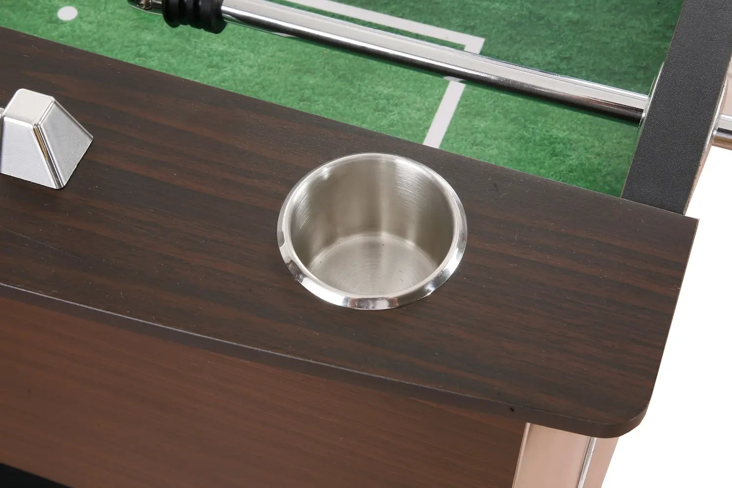 Stainless steel recessed drink holder on a foosball table with a dark wood grain finish and green playing surface partially visible.