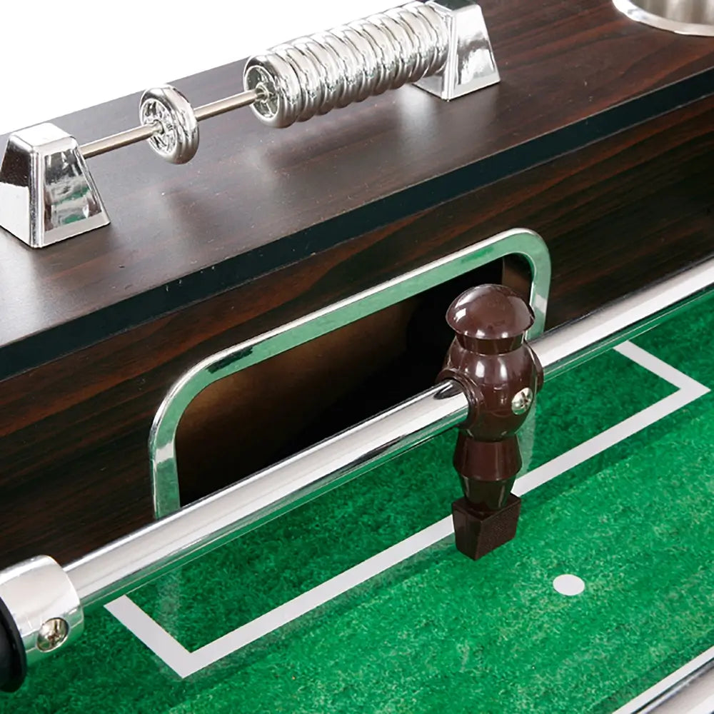 Manual chrome score counter and goal opening on a foosball table above the green playing field with white markings and dark brown player figure.