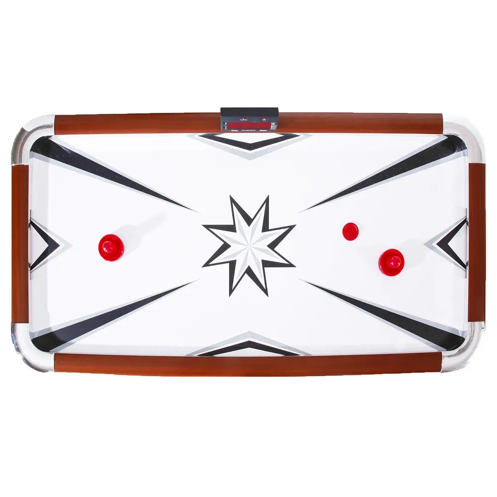 Top-down view of an air hockey table with red pushers and pucks on a white glossy playfield featuring black geometric star design. Includes digital scoreboard and brown wooden side rails with chrome accents.