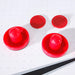 Close-up of two red air hockey pushers and two red pucks placed on the white playfield with micro-perforations for air flow. Essential accessories for playing air hockey.