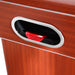 Close-up of the puck return slot on the air hockey table’s wood-paneled side, containing a red puck. Chrome trim outlines the slot for visual contrast.