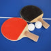 Close-up of table tennis paddles with red and black rubber faces and two white ping pong balls, placed on blue playing surface.