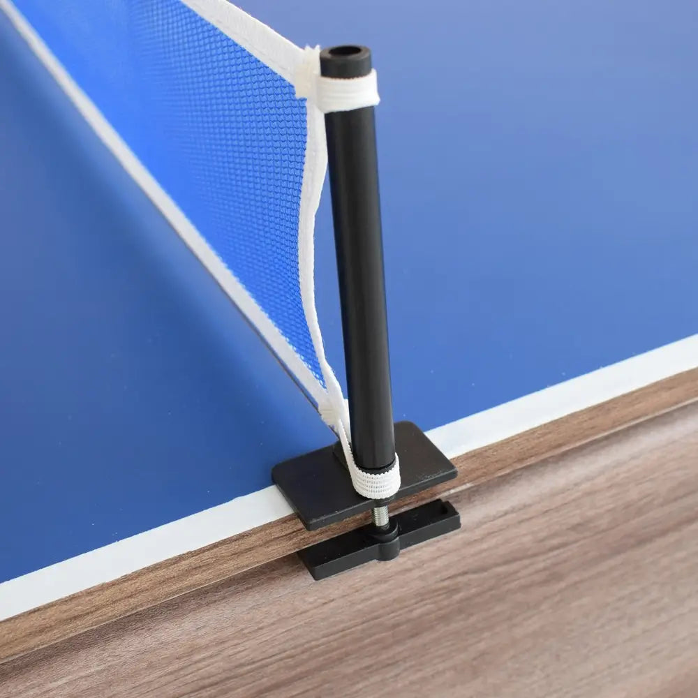 Close-up of clamp-on ping pong net post securely attached to edge of blue table tennis top with wood grain table base.