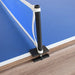 Close-up of clamp-on ping pong net post securely attached to edge of blue table tennis top with wood grain table base.