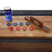 Shuffleboard accessories including 4 blue pucks, 4 red pucks, a table brush, and a can of Hathaway Surface Ice shuffleboard wax on a wood playfield.