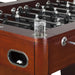 Glass of ice water placed in built-in stainless steel drink holder on espresso-finish foosball table corner, designed for player convenience.