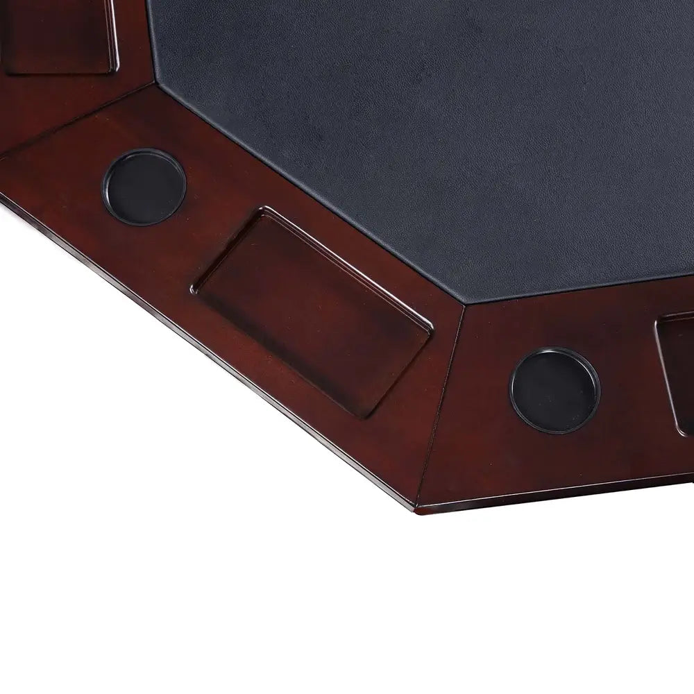 Close-up of black faux leather poker playing surface with integrated chip trays and rubber-lined drink holders in dark oak wood finish.