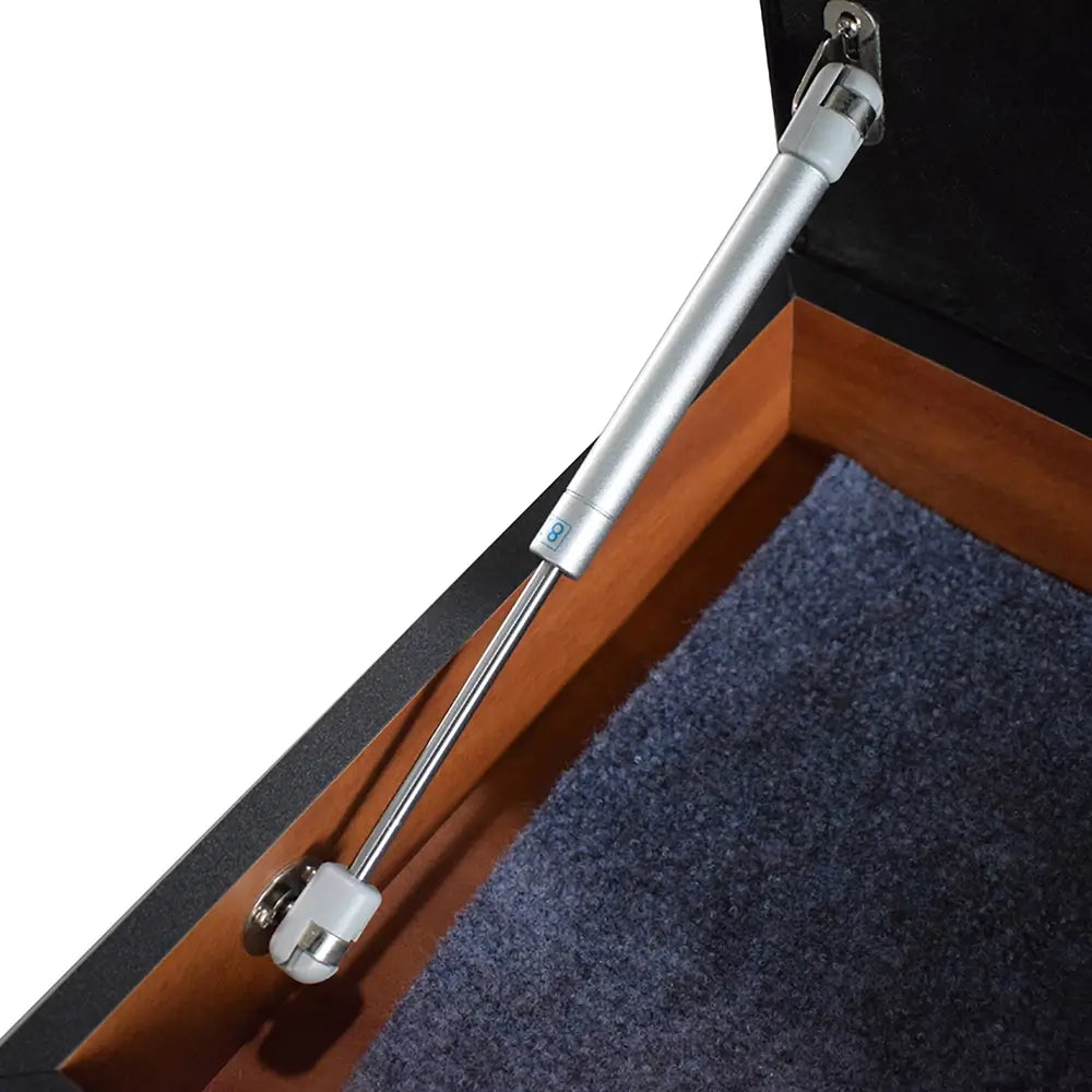 Close-up of gas spring hinge installed inside game table bench for soft-close functionality, with carpeted interior lining.