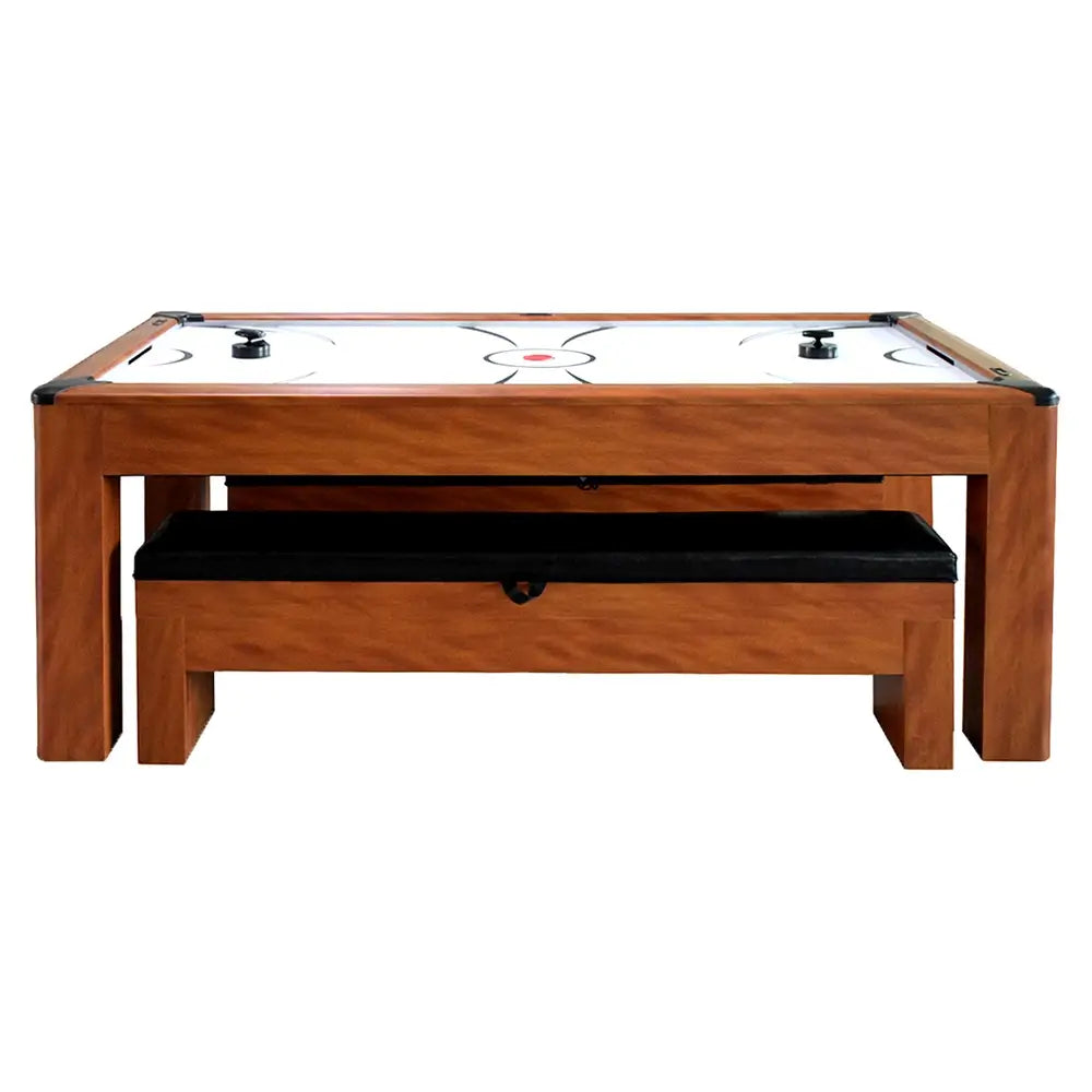Air hockey table with natural wood finish and black cushioned storage bench, shown in game mode with pucks and strikers on playfield.