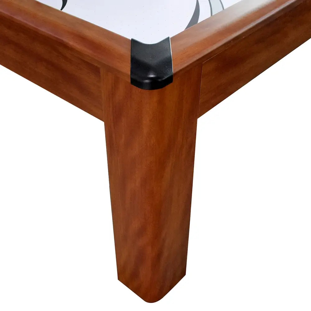 Close-up of corner leg and rail on wood-finish air hockey table with black protective corner caps and white playfield with black graphics.