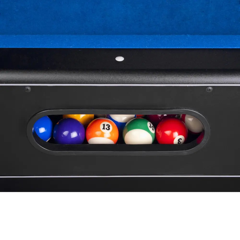Close-up of the internal ball return system on the Hathaway Hustler pool table, showing colorful racked billiard balls stored behind a black oval cutout in the side cabinet.
