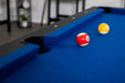 Close-up of two billiard balls (#11 red stripe and #9 yellow stripe) on blue wool-blend felt near a corner pocket with black plastic liner and black top rail on the Hathaway Hustler pool table.