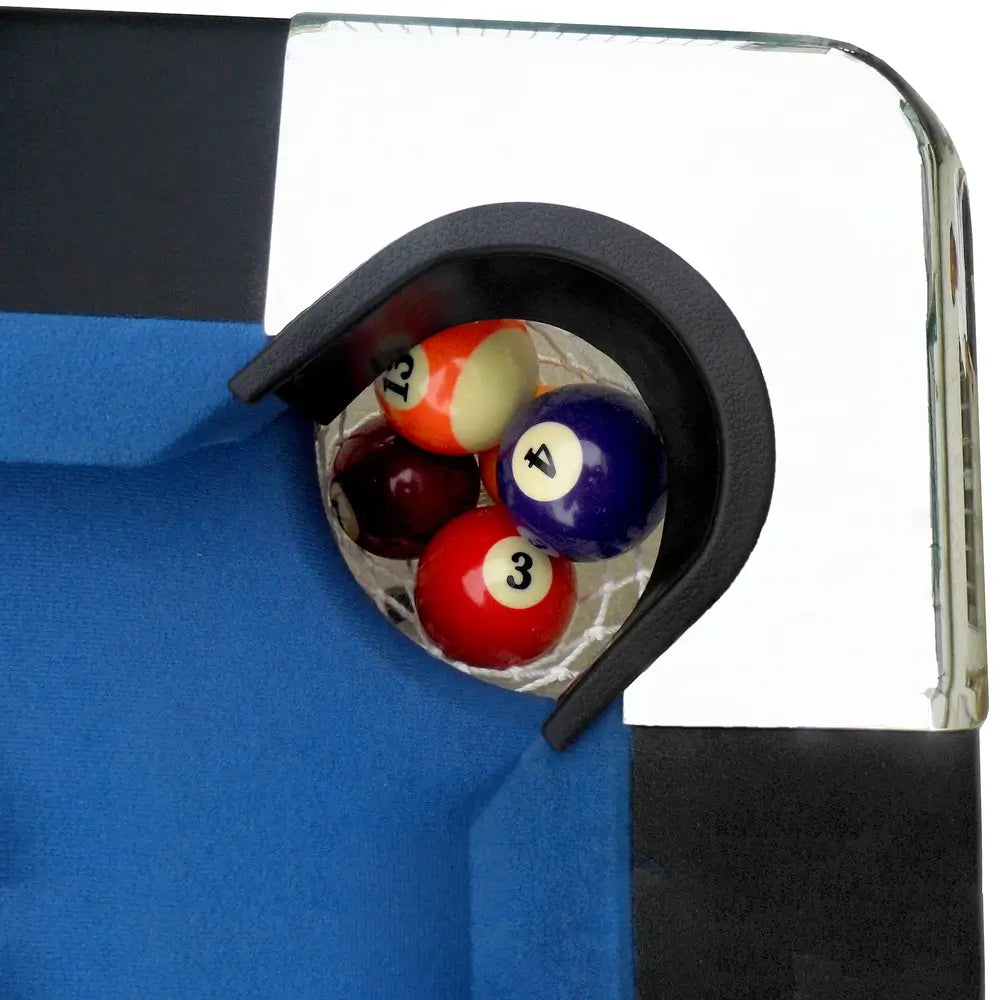 Top-down view of corner pocket on Hathaway Fairmont 6-ft Pool Table filled with multiple balls, chrome-plated corner detail and blue felt surface visible.