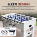 White and silver foosball table with soccer-style blue playfield set on backyard patio, includes two 36mm foosballs and protective nylon cover.
