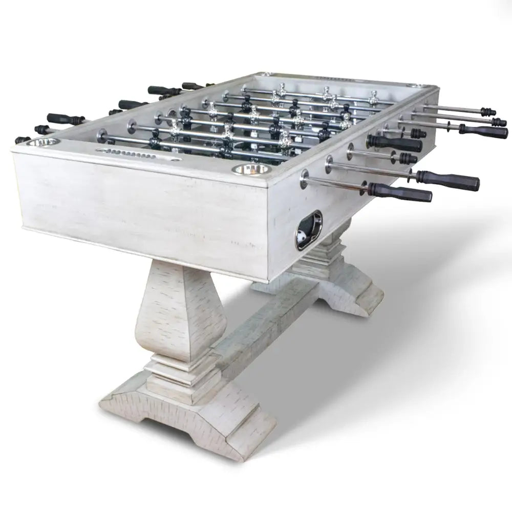 Full angled view of whitewashed farmhouse foosball table with sculpted dual pedestals, chrome rods, built-in drink holders, and classic arcade design.