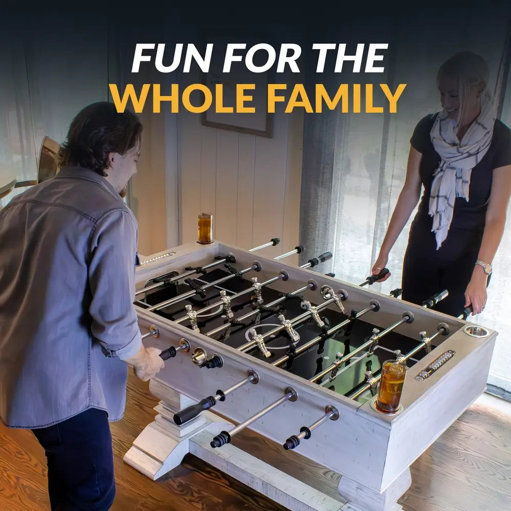 Man and woman enjoying a match on a modern farmhouse foosball table with chrome-plated rods and black and silver players in a casual home setting.