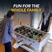 Man and woman enjoying a match on a modern farmhouse foosball table with chrome-plated rods and black and silver players in a casual home setting.