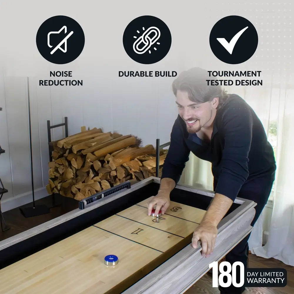 Man playing on Hathaway Montecito 12-ft Shuffleboard Table – Driftwood, emphasizing noise-reducing padded gutters, durable construction, and tournament-tested design in a home setting.