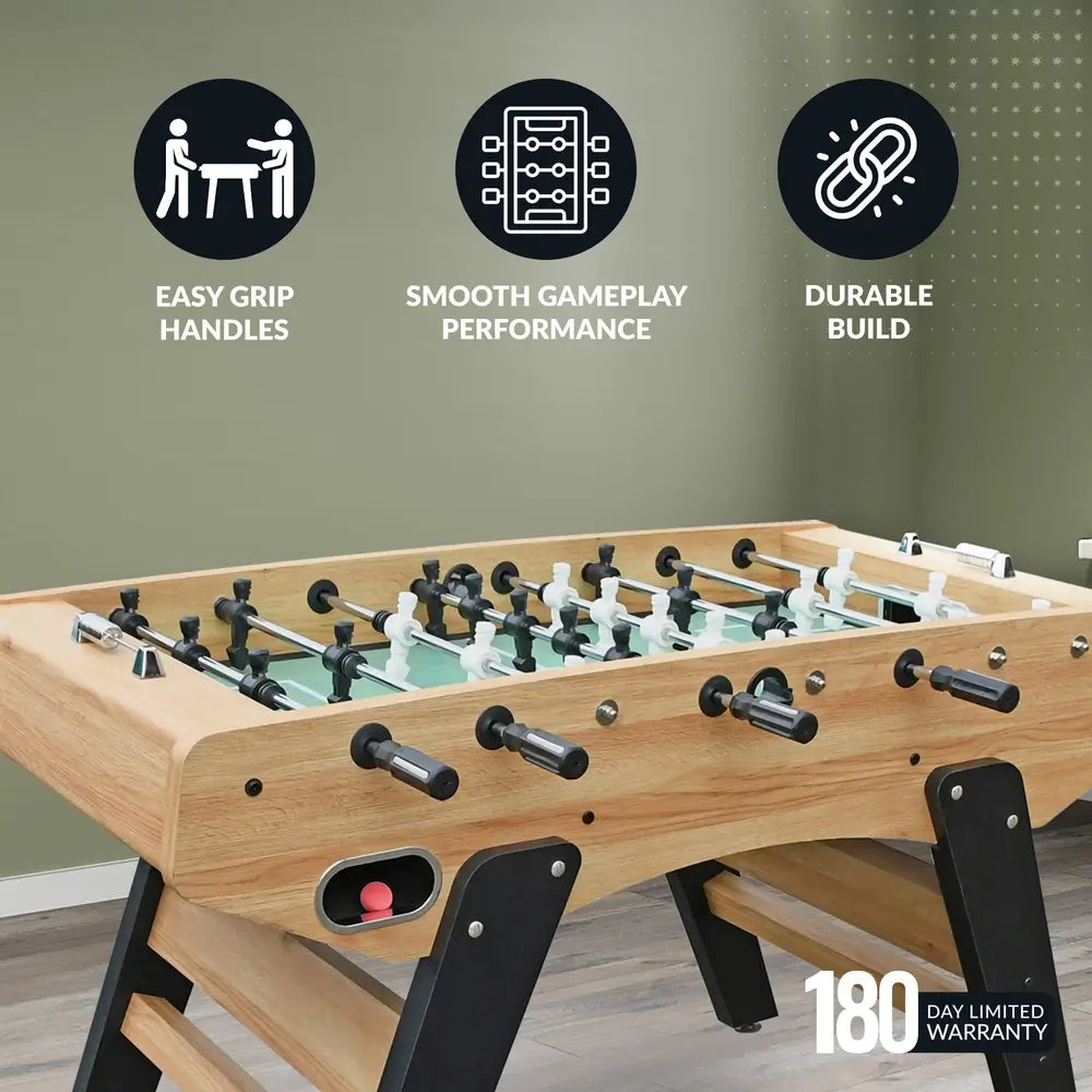 Foosball table in light oak finish with black-and-white players, red ball in ball return slot, and feature icons showcasing easy-grip handles, durable build, smooth gameplay, and 180-day limited warranty.