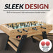 Light oak foosball table with black ladder-style legs and red ball in return slot; features sleek, modern design and includes two 36mm ABS foosballs for fast-paced gameplay.