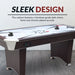 Sleek air hockey table with furniture-grade dark cherry wood finish, chrome accents, and starburst playfield design. Includes two black ergonomic pushers, red pucks, digital control panel, and arched pedestal-style legs with leveling feet. Text overlay: “SLEEK DESIGN.”