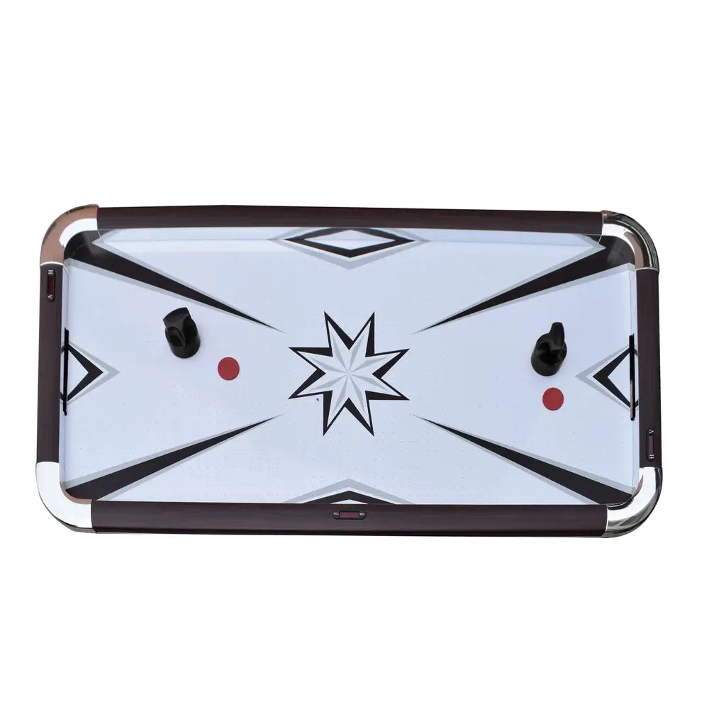 Top-down view of an air hockey table with a white starburst playfield design, two black ergonomic strikers, and two red pucks. Table features dark wood rails and chrome corners for a modern arcade look.
