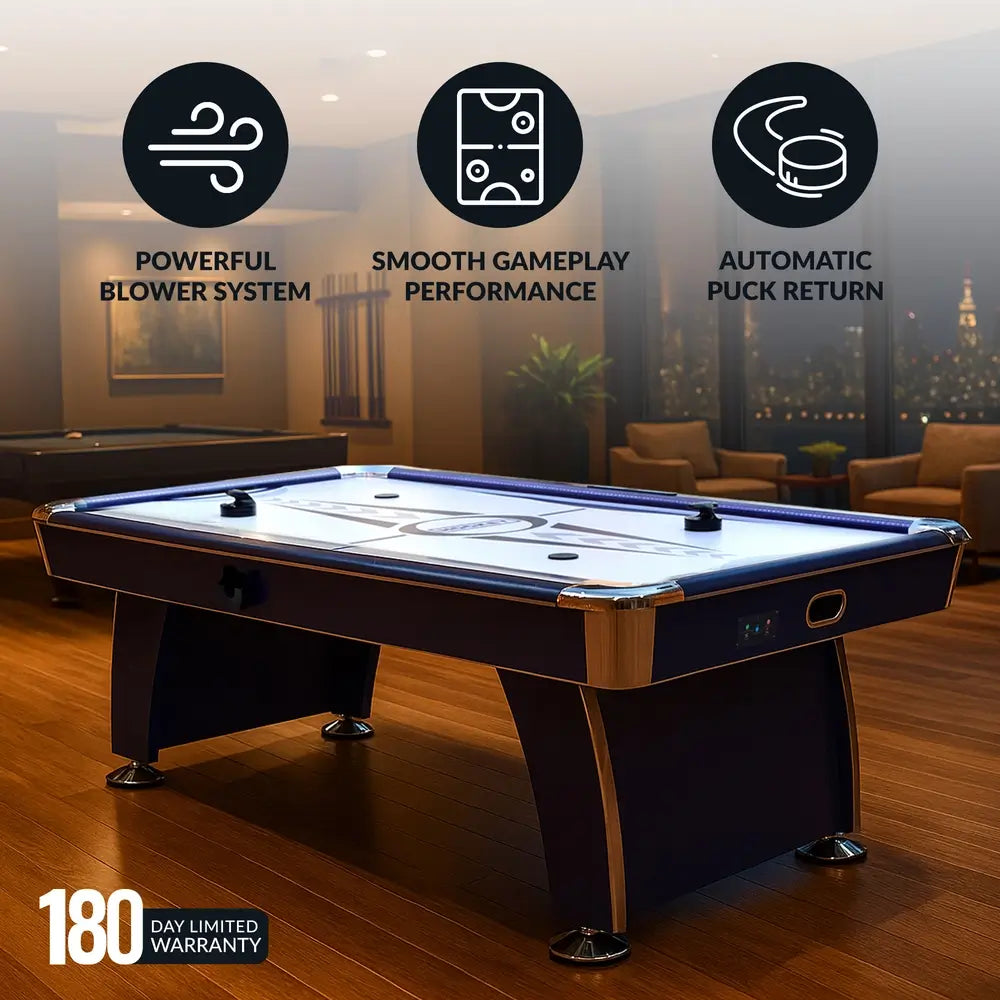 Phantom II air hockey table showcased in a luxury game room with city skyline view. Overlay icons indicate powerful blower system, smooth gameplay performance, and automatic puck return. Text displays 180-day limited warranty.