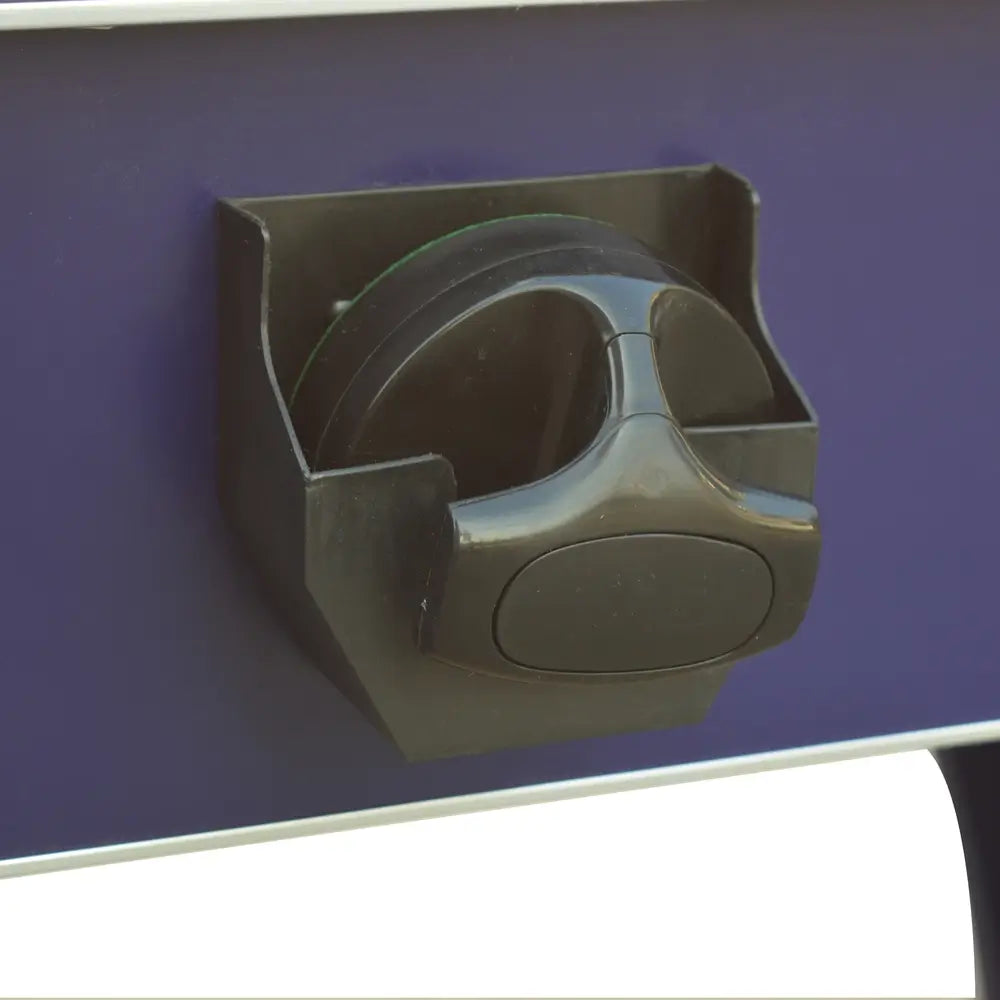 Mounted storage holder attached to the side of the air hockey table, securely holding a black striker for convenient access during play.