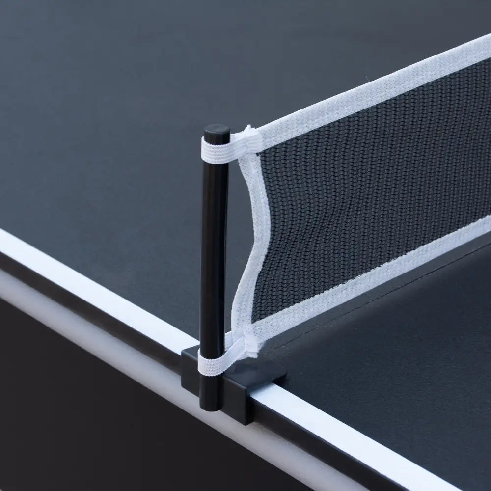 Detailed view of black and white mesh net system clipped onto the table tennis surface of a convertible game table, showing durable post and elastic attachment.
