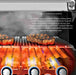 Close-up of Broil King Flav-R-Wave stainless steel cooking system with burners and steaks on the grill grates for even heat distribution.