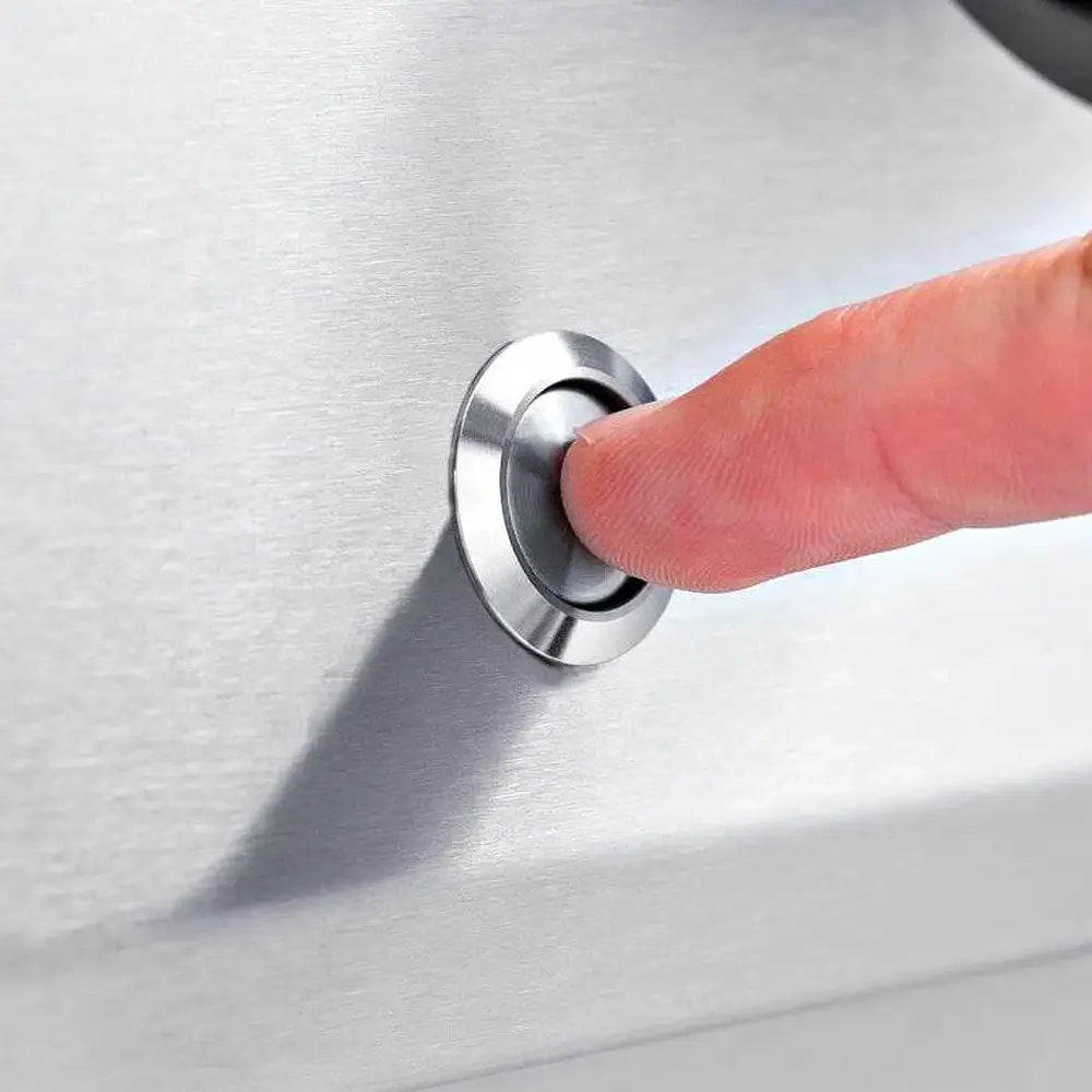 A finger pressing the Sure-Light electronic ignition button on the stainless steel control panel of a Broil King Imperial 690 grill.
