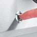 A finger pressing the Sure-Light electronic ignition button on the stainless steel control panel of a Broil King Imperial 690 grill.