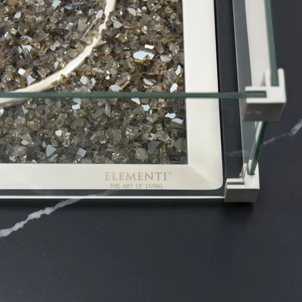 Close-up top view of bronze fire glass and a glass wind guard corner on an Elementi porcelain fire table.