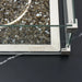 Close-up top view of bronze fire glass and a glass wind guard corner on an Elementi porcelain fire table.