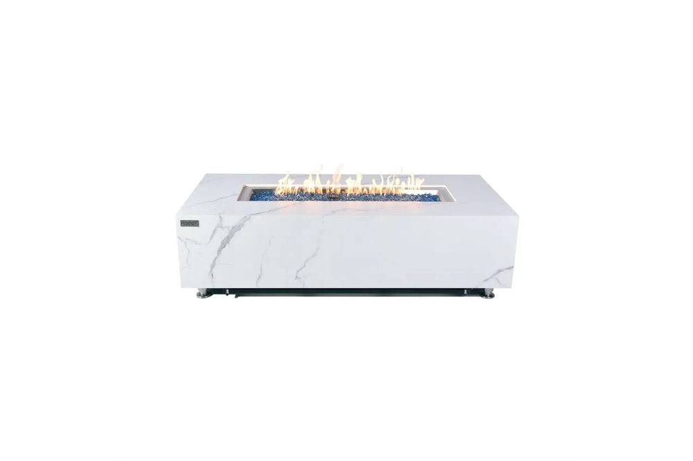 Studio product shot of the 60,000 BTU Elementi Plus Carrara Bianco fire pit with a lit central flame and blue glass fire media on a white background.